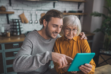 Young handsome man in grey shirt and his mom searfing internet