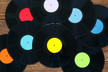 Retro vinyl discs records on wood table background. Multicolored labels. Top view.