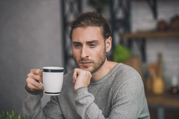 Young bearded handsome man in grey looking disturbed