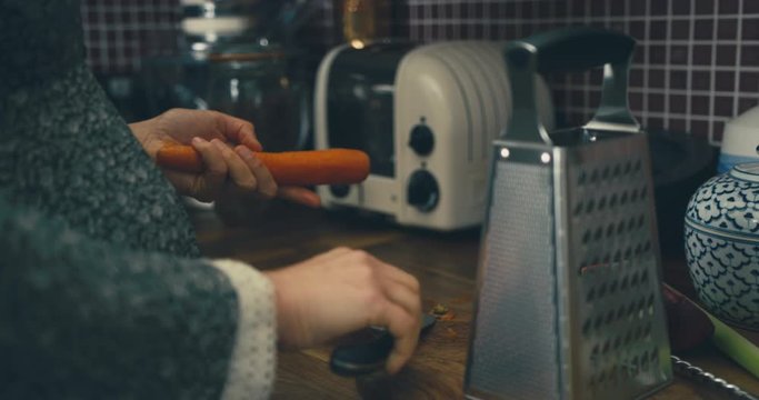 Young womann grating a carrot in her kitchen