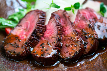 Cooked fillet of beef tenderloin sliced on a plate with an Italian salad. Barbecue dry aged wagyu...