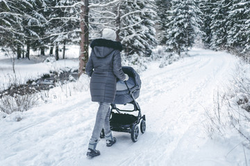 Fototapeta na wymiar Mother with pram in snowy forest