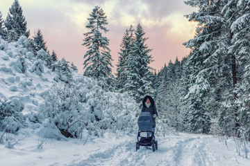 Mother with pram in snowy winter forest