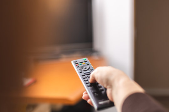 Hand pointing a tv remote control towards the television