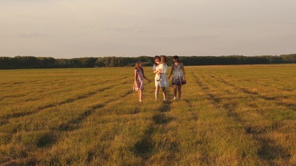 Children and mom are playing in the meadow. concept of a happy family. mother and little daughter with sisters walking in park. Happy young family with a child walking on summer field.
