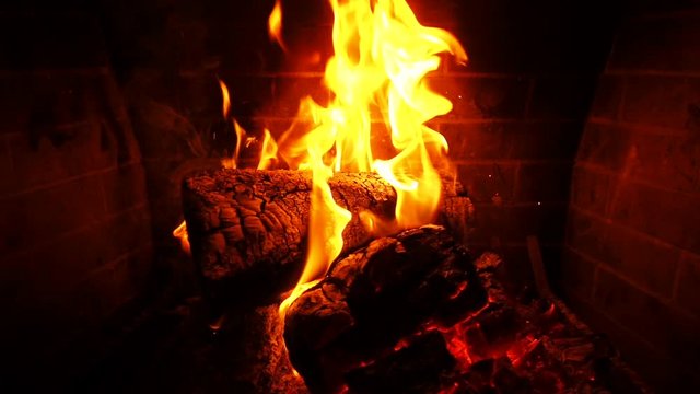 Slow motion video of cosy fireplace with reddish flame burning during winter holidays