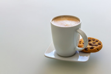 A cup of cappuccino cofee with cookie on a saucer. Copy space. Light background