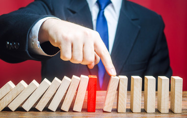 Businessman restarts the process of falling dominoes. Start work after stopping. After the weekend....