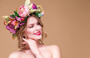 Happy beautiful young woman model with bright flowers on her head smile on the ocher color...