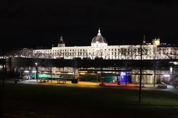Fototapeta premium Lyon la nuit - L'ancien hôpital de l'Hôtel Dieu au bord du fleuve Rhône avec en premier plan les bâteaux le long du quai Victor Augagneur - Ville de Lyon - Département du Rhône - France