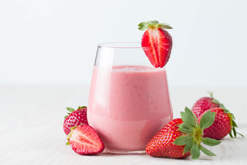 Glass of fresh strawberry milkshake, smoothie and fresh strawberries on pink, white and wooden...