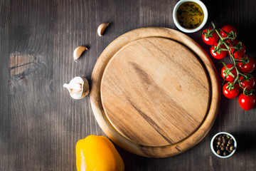 Wooden Cutting Board with Fresh Herbs and Raw Vegetables on Rustic Wood Table. Top view. Cooking background.
