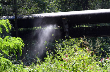 Rusty, cracked pipes spray water in nature. Water supply network