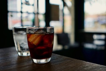 A glass of sparkling water and a glass of water with ice on the wooden table in the restaurant