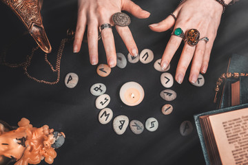 Astrology and esotericism. Female witch hands conjure over the rune circle. On a black background...