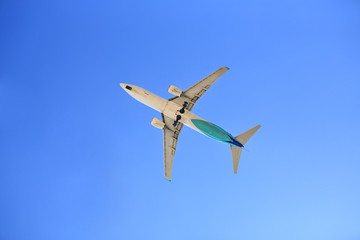Airplane flying on blue sky. Seen from below.