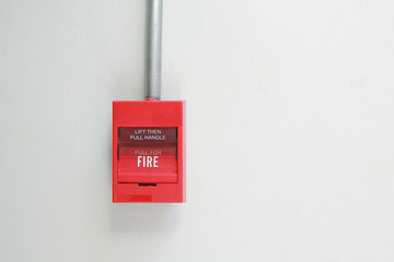 Fire alarm switch on white cement wall.