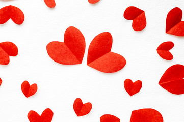 White surface covered with multiple red and pink heart shaped paper confetti. Postcard Valentine's Day