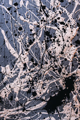 Picture painted using the technique of dripping. Mixing different colors white and black. Lines and spots. Vertical orientation.
