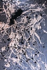 Picture painted using the technique of dripping. Mixing different colors white and black. Lines and spots. Vertical orientation.