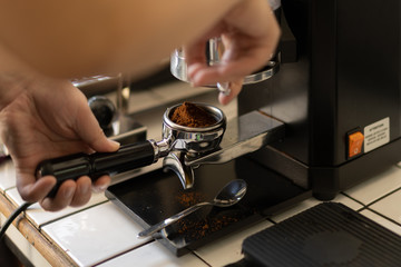 Fototapeta na wymiar Barista grinding fresh coffee bean into portafilter for espresso