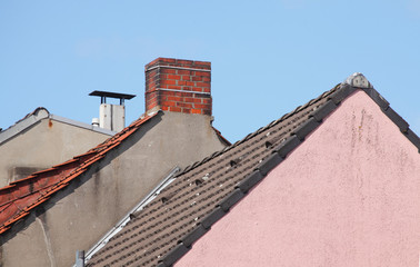 Schornsteine, Dächer, rosa Hauswand, Blauer Himmel, Deutschland