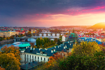 Obraz premium Autumn view to Charles bridge on Vltava river in Prague, Czech Republic. Autumn view to Charles Bridge, Prague old town and Vltava river from Letna park (Letenske sady) at sunset with colorful sky.