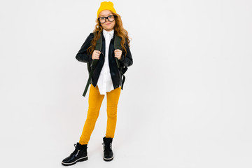 Teenager caucasian girl with yellow hat holds a big backpack in her hands isolated on white background