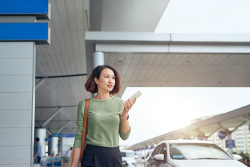 Asian woman is checking her smartphone as she waits in airport in Asia.