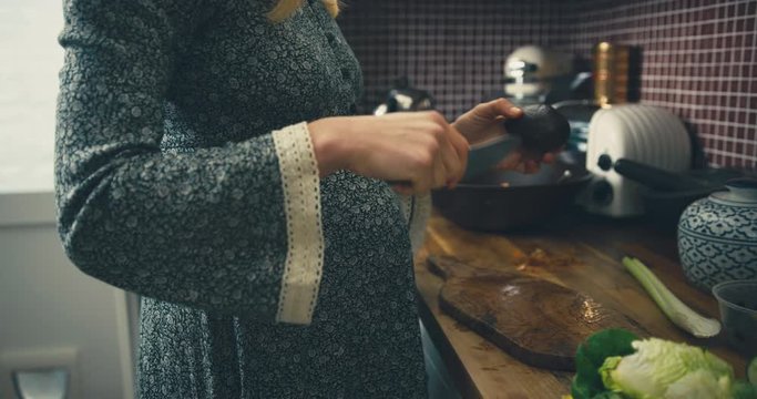 Pregnant woman in kitchen cutting avocado in half