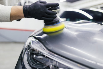 Car detailing - Worker with orbital polisher in auto repair shop.