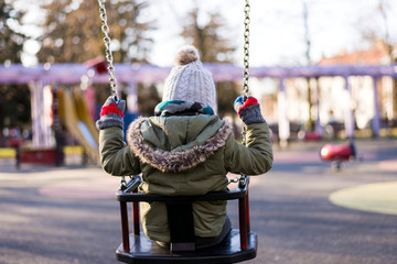 Lonley child on swing on cold day