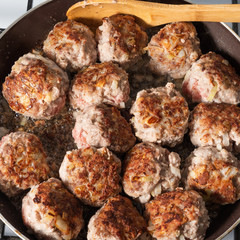 Fried meat large meatballs in a pan on a gas stove, close-up