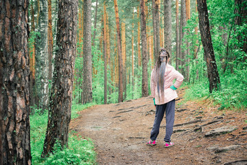 Cute girl on forest clearing among the trees on hike.