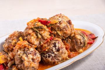 Delicious meatballs in homemade tomato sauce baked with grated cheese and rosemary leaves on a dish close-up - american cuisine
