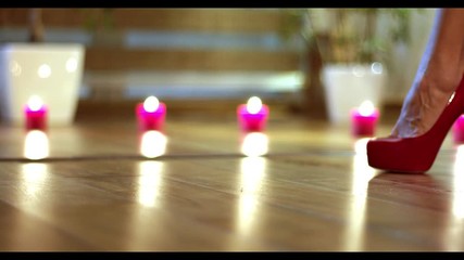 Close-up of shapely female legs walking in sexy red high heels on romantic background (candles and fume)