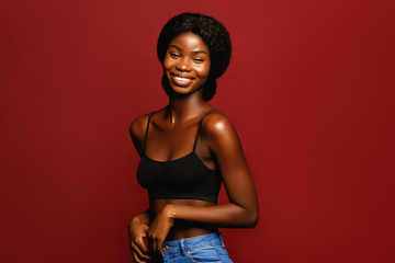 Beauty. African American beautiful woman portrait. Brunette curly haired young model with dark skin and perfect smile against red background