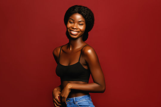 Beauty. African American Beautiful Woman Portrait. Brunette Curly Haired Young Model With Dark Skin And Perfect Smile Against Red Background