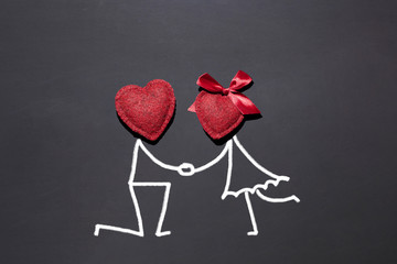 Two red textured hearts on a black chalk board and drawn figures of lovers, a symbolic image of a...