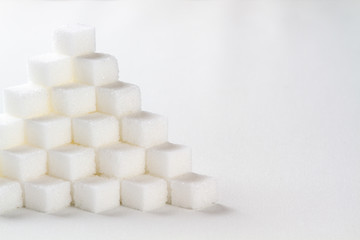high key closeup of a pyramid of sugar cubes arranged in a cube pattern