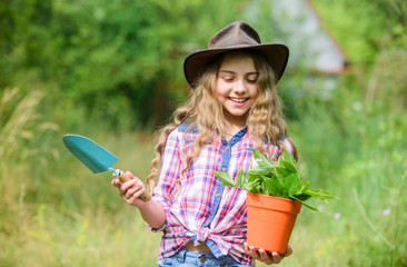 Planting plants. Happy childhood. Child in hat with shoulder blade small shovel hoe. Happy smiling...