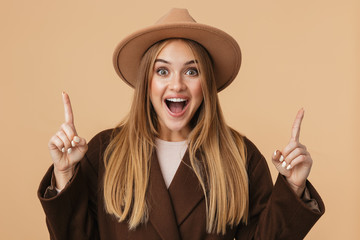 Image of young girl in hat smiling and pointing fingers upward