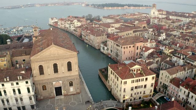 Aerial, drone shot over a channel and buildings, towards a harbor, on a sunny evening, in Venezia, Italy
