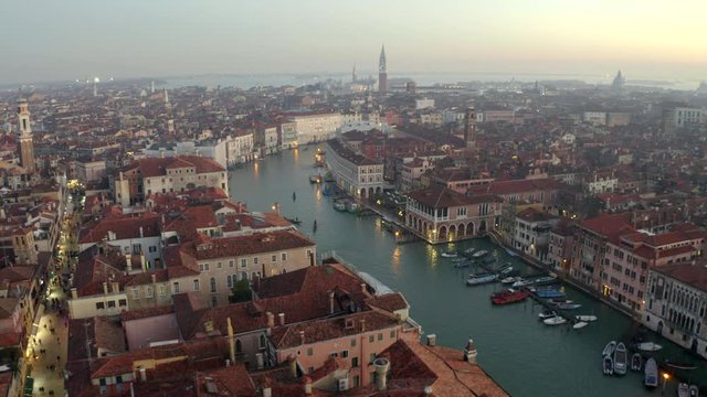 Aerial, drone shot overlooking gondolas on the Canalaso, the canal grande di Venezia, city lights on, on a sunny evening, in Venice city, Italy