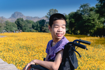 Asian special child on wheelchair smiling on his face with flower fields background, Travel on a holiday with his father, Life in the education age of disabled children, Happy disabled kid concept.