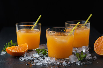 Tangerine cocktails with sliced mandarins, ice, mint on a black wooden table