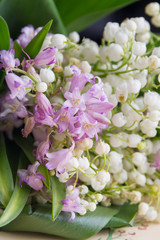 Bouquet of small spring flowers close-up. Lilies of the valley and purple flowers.