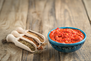 Traditional spicy harissa sauce in oriental bowl on rustic light background with spices. Maghreb...