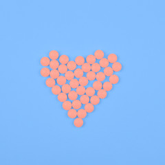 Medical background or banner. Pink Pills in form of heart on blue background.