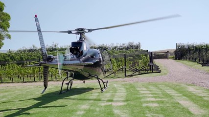SLOWMO - Black private helicopter from behind ready to take off from vineyard on Waiheke Island, New Zealand
